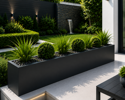 Modern garden with black rectangular planter, grass, and a small waterfall.  Patio with a rectangular planter