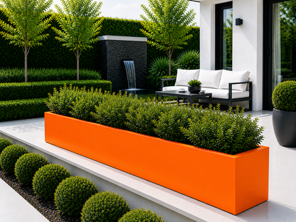 Modern outdoor setting with orange planter, white sofa, and greenery.