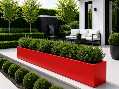 Modern outdoor setting with a red planter, greenery, and a white sofa.